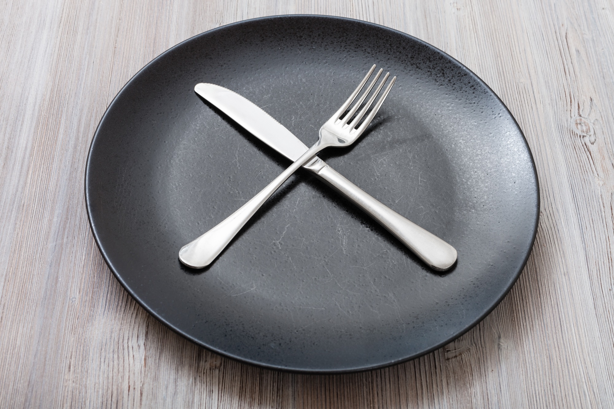 black plate with crossing knife, spoon on gray